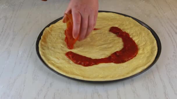 Frau gießt Pizza Marinara auf rohen Teig. — Stockvideo