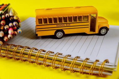 Okul kavrayışına geri dönelim. Not defteri ve renkli kalemleri olan sarı oyuncak otobüs.