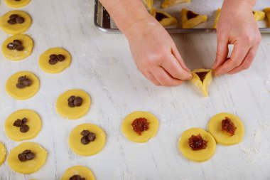 Purim için reçelli hamantaschen kurabiyesi ve çikolata cipsi yapıyorum. Yahudi bayramı konsepti,