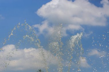 Mavi gökyüzü arka planındaki çeşmede parlayan su.