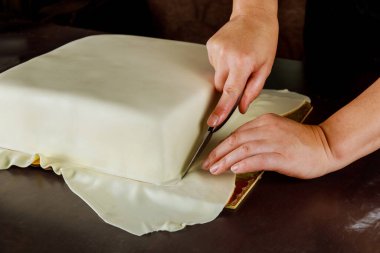 Kare pastaya beyaz fondöten kesen kadın. Düğün pastası yapma tekniği..