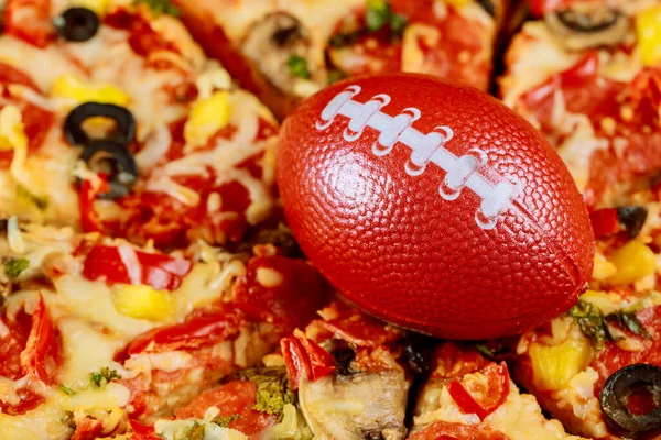 Supreme pizza with football ball for american football party. Close up.