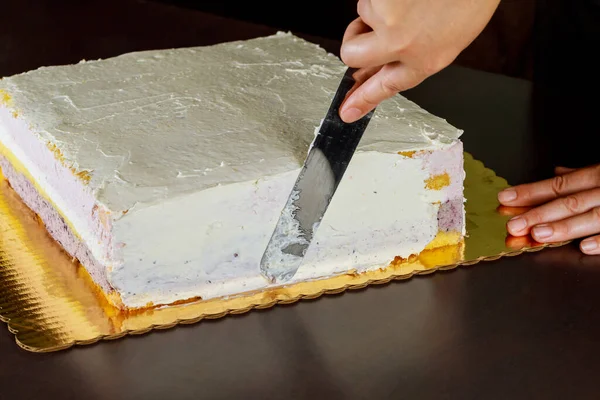 Fırıncı beyaz kremalı pastayı spatulayla kaplıyor..