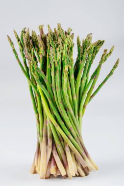 İzole edilmiş beyaz zeminde pişmemiş taze kuşkonmaz..