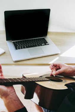 Adam bilgisayarı kullanarak gitar çalmayı öğreniyor