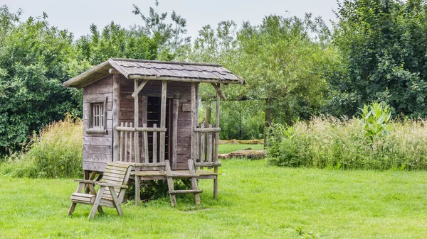 Gemütliches Holzspielhaus in einem grünen Garten — Stockfoto