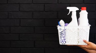 ev temizliği, siyah tuğlalı arka planda temizlik malzemeleri olan bir kutu.