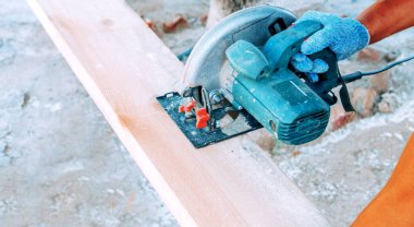 Dairesel testere tahta adamın elini eldivenle keser.