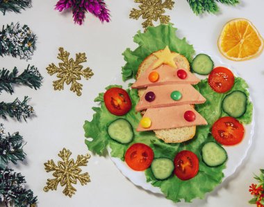 Noel ağacı yiyen sandviç. İçinde ekmek, sosis ve peynirden yapılmış yenilebilir Noel ağacı olan komik bir sandviç. Çocuklar için kahvaltı fikri. Yeni yıl yemek arkaplan manzarası. tatil, tatil.