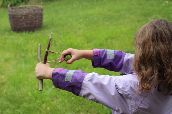 Kız, yeşil çimenlerin arka planına karşı elastik bir bant takıyor.
