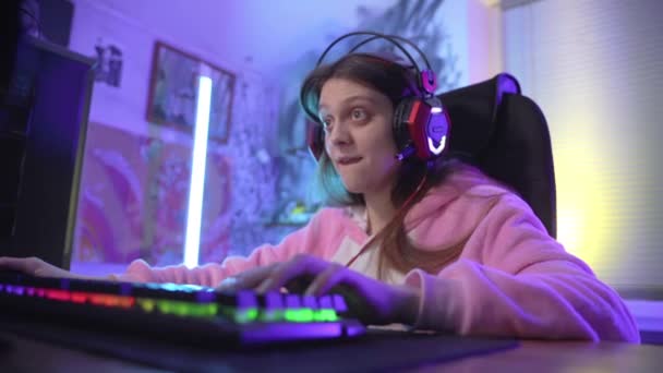 Una joven gamer emocionalmente juega un juego de ordenador . — Vídeos de Stock