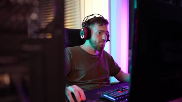 Ein junger Gamer spielt emotional am Computer. — Stockvideo