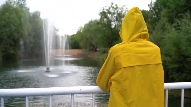 Sarı yağmurluklu genç bir kız çeşmelere bakıyor.. — Stok video