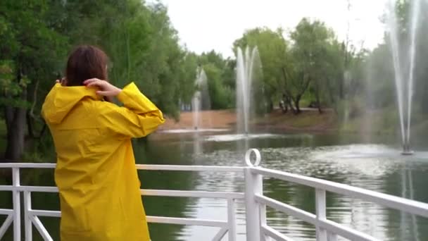 Kız bir başlık takıyor ve çeşmeli gölete bakıyor. Yeşil Park — Stok video