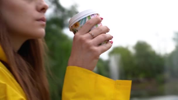 The girl holds a glass of coffee in her hand, brings it to her lips and drinks. — Stock Video