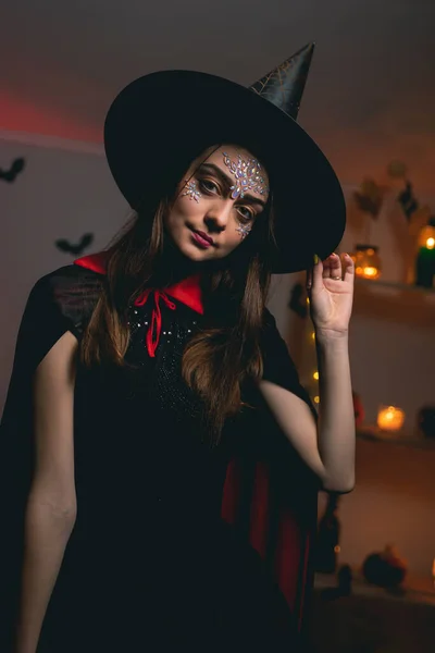 Une jeune femme en costume de sorcière de carnaval tient son chapeau noir dans les deux mains — Photo