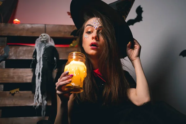 Cadı kostümü giymiş şaşırmış bir kız şapkasını elinde tutuyor. — Stok fotoğraf