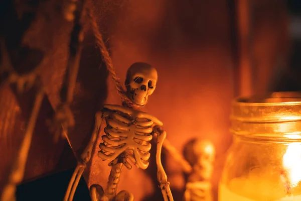 Oyuncak insan iskeleti mumların yanında bir ipe asılı duruyor. Cadılar Bayramı temalı arkaplan — Stok fotoğraf