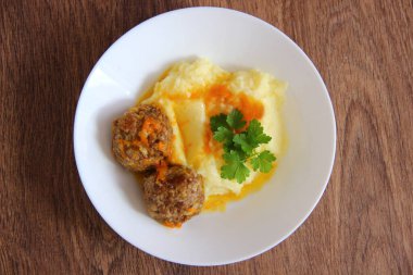 Köfteli patates püresi ve beyaz tabakta sos ve ahşap masa, üst manzara.