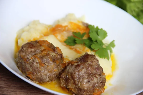 Ev yapımı köfteler patates püresi, havuç ve maydanozla süslenmiş soğan sosu.