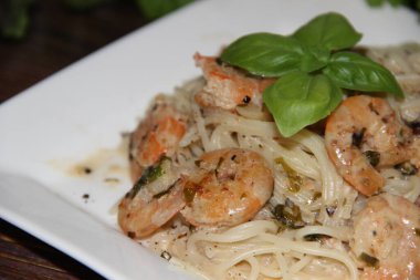 Karidesli spagetti ve taze fesleğenli otlar, yakın çekim manzaralı.