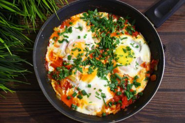 Sebze ve yumurtaların Shakshuka 'sı ahşap bir masada tavada, üst manzara