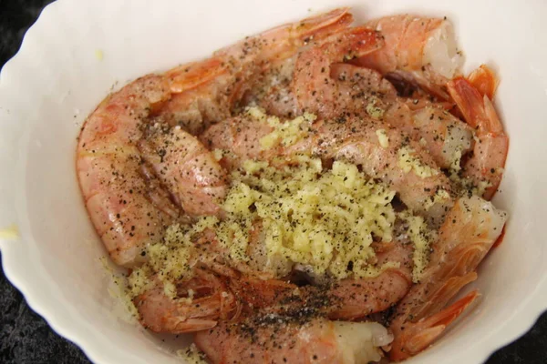 Large cooked-frozen shrimps in a shell without heads in a marinade of garlic and spices in a white Cup