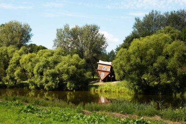Dukora, Belarus - 18 Temmuz 2020: Dukora Maentak Müzesi Minsk bölgesi baş aşağı ev binası. Gölün önündeki parkta turistik bir eğlence. Güneşli güzel hava, yeşil ağaçlar ve mavi gökyüzü