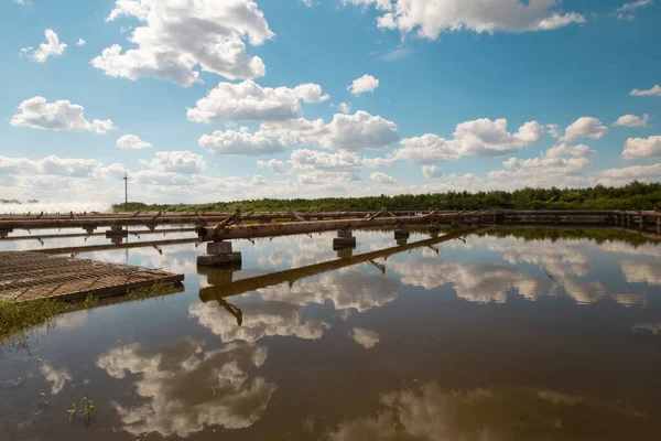 Dukora Belarus Minsk Region. Thermal energy electricity station plant cooling system fountains and lake in sunny summer warm weather. Blue sky and clouds reflecting in the water. Nature and industry
