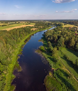 Venta nehrinin kırsal manzarası ılık bir yaz gününde ağaçlarla dolu güzel bir çevrede akıyor. Fotoğraf Letonya 'da çekildi.