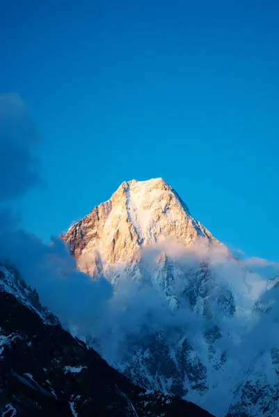 Dağların zirveleri, mavi gökyüzü ve güzel bulutlar. Pakistan Karakorum 'da kış turizmi. Dikey manzarada kar vadisi.