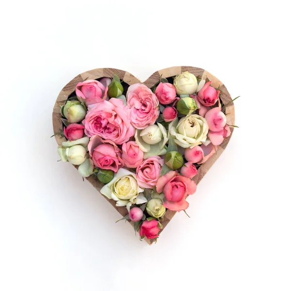 Beyaz arka planda tahta kalp çerçevesinde gül çiçekleri