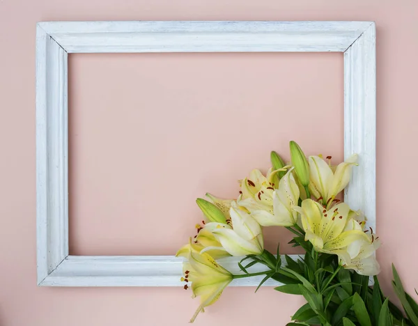 Taze beyaz zambaklı yaratıcı kart ve pastel pembe arka planda resim çerçevesi