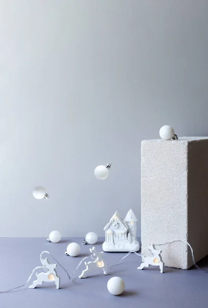 Beyaz geyikli modern minimalist Noel kompozisyonu, ışıklı kışlık ev ve dekorasyon baloları Alternatif iş tebrik kartı, fotokopi alanı. Monokrom yeni yıl modeli. Gri arkaplan