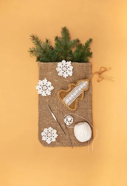 Noel yatağında çuval bezi, köknar dalları, el yapımı Noel ağacı ve portakal arka planında örgü kancası ve iplikle örülmüş kar taneleri vardı. Sıfır israf Noel dekoru. Çevre dostu yeni yıl.