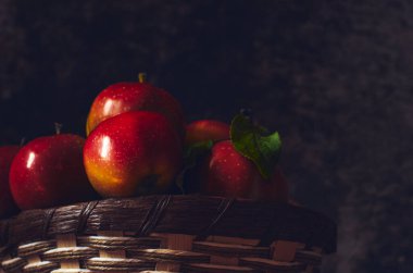 Tahta bir bankta olgun kırmızı elmalarla dolu sepet.