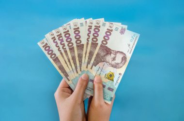 UAH Ukrayna 'nın parası elinde, Ukrayna banknotu mavi arka planda izole edilmiş.