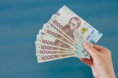 UAH Ukrayna 'nın parası elinde, Ukrayna banknotu mavi arka planda izole edilmiş.