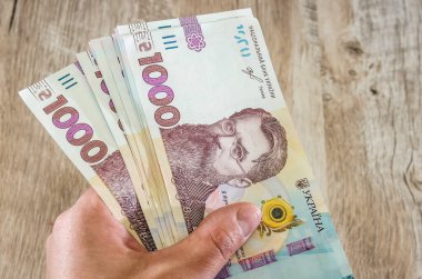 Elinde ahşap bir arka planda 1000 Hryvnia. Yakın plan..