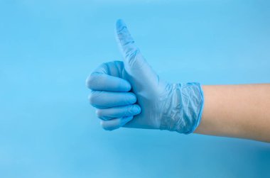 Mavi eldivenli cerrahın elinde mavi arka planda izole edilmiş, tamam işareti var. Uzayı kopyala Metin için yer.