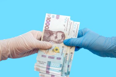 Tıbbi eldivenli iki kadın ve mavi arka planda izole edilmiş 100 dolarlık banknot. Yozlaşma ya da karantina kavramı, Covid 19.