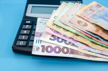 Hesap makinesinde farklı hryvnialar. Mavi arka plan. Yakın plan. Tasarruf kavramı.