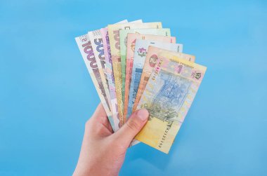 eldeki farklı hryvnialar mavi bir arkaplanda izole edilmiş.