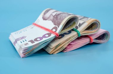 Mavi arka planda izole edilmiş elastik bir bant ile bağlanmış 1000, 500, 200 Hryvnia. Yakın plan. Hryvnialar yuvarlandı