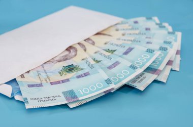 Mavi arka planda beyaz bir zarf içinde 1000 Hryvnia. Yakın plan..