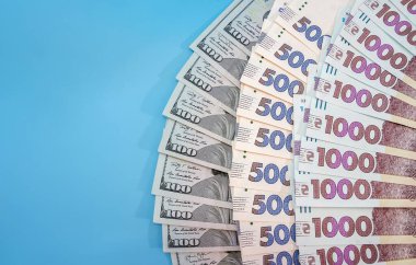 Çok güzel bir şekilde mavi arka planda 1000, 500 hryvnia ve 100 dolarlık banknotlar serpiştirdim. Boşluğun kopyası.
