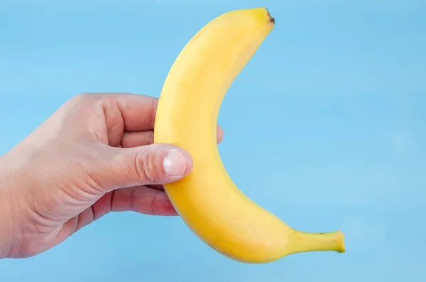Gul Banan Handen Isolerad Blå Bakgrund Uppfattat Utrymme Provningsplats — Stockfoto