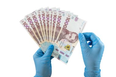 Mavi eldivenli eller beyaz arka planda izole edilmiş 1000 Hryvnia banknotunu tutuyor..