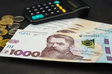 UAH Ukrayna 'nın parası 1000 Hryvnia, hesap makinesi ve siyah arka planda paralar. Ukrayna banknotu.