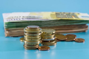 Mavi arka planda Avro banknotları ve bozuk paralarla dolu bir yığın. İş konsepti. Tasarruf kavramı. Çok para..